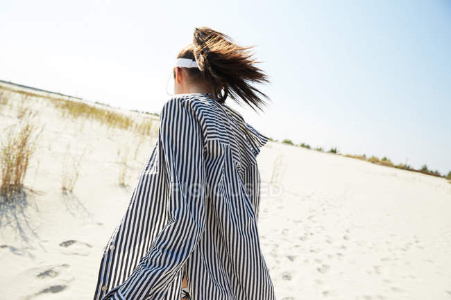 Femme en visière marchant sur la plage — Photo de stock