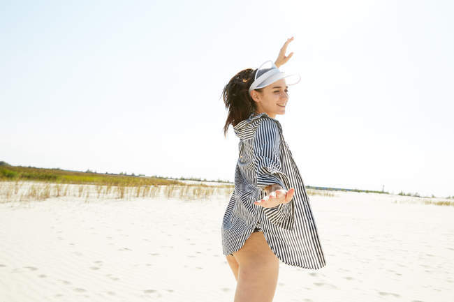 Donna in visiera bianca in posa sulla spiaggia — Foto stock