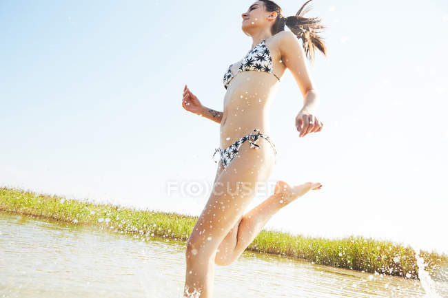 Frau im Badeanzug läuft im Wasser — Stockfoto