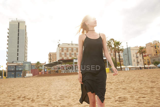 Belle femme en robe noire debout sur la plage publique à Barcelone — Photo de stock