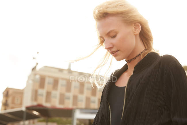 Низкий угол зрения привлекательной женщины, стоящей на улице в солнечный день — стоковое фото