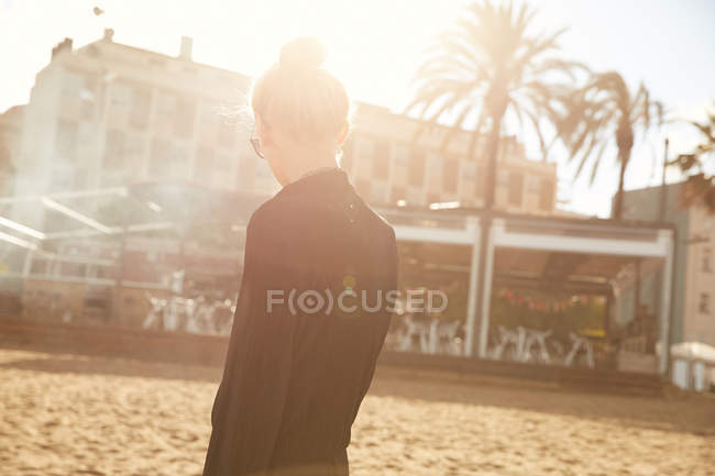 Portrait de jeune femme en lunettes de soleil fumant cigarette électronique sur la plage à Barcelone — Photo de stock