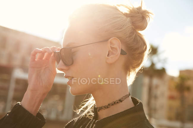 Vista lateral da mulher atraente usando óculos de sol na rua no dia ensolarado — Fotografia de Stock