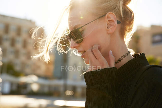 Retrato de mujer joven en gafas de sol caminando por la calle en barcelona - foto de stock