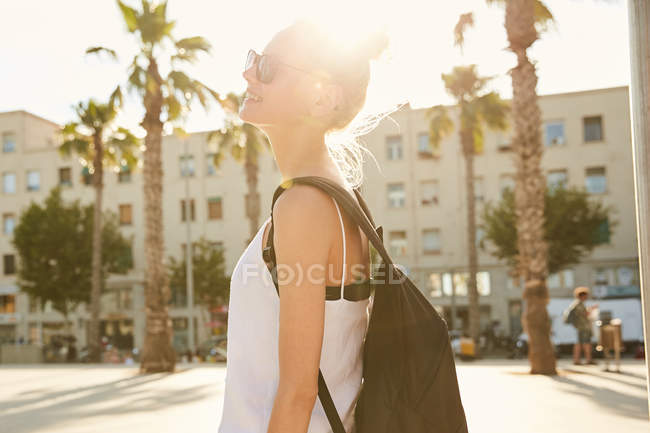 Seitenansicht der blonden jungen Touristin mit schwarzer Tasche, die auf der Straße in Barcelona steht — Stockfoto