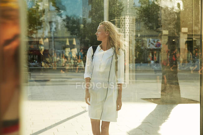 Junge frau steht neben glas auf der straße in barcelona und schaut weg — Stockfoto