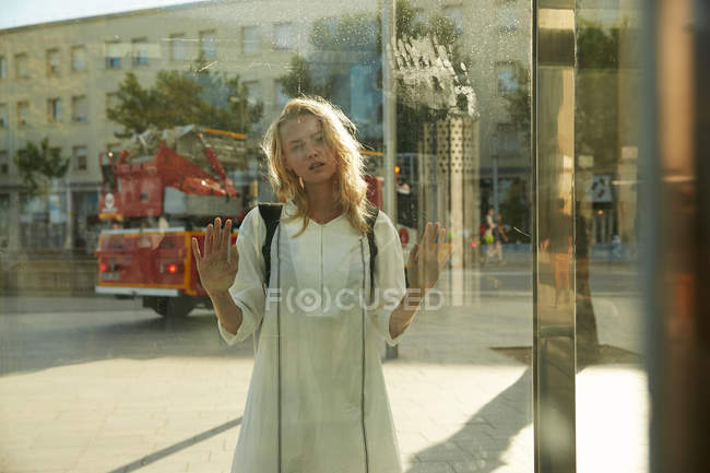 Young woman standing near glass on street in barcelona — Stock Photo