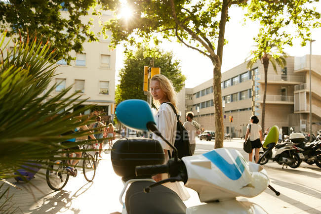 Vista laterale della donna in piedi vicino moto parcheggiate in strada a Barcellona — Foto stock