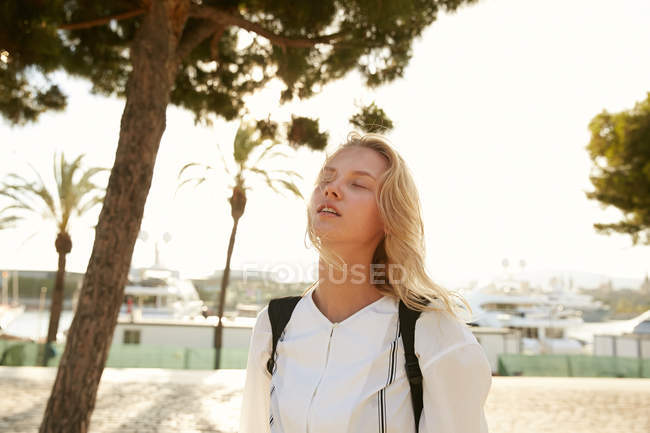 Attractive woman standing on quay in barcelona with closed eyes — Stock Photo