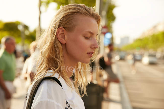 Vista laterale della donna bionda in piedi con borsa sulla strada a Barcellona — Foto stock