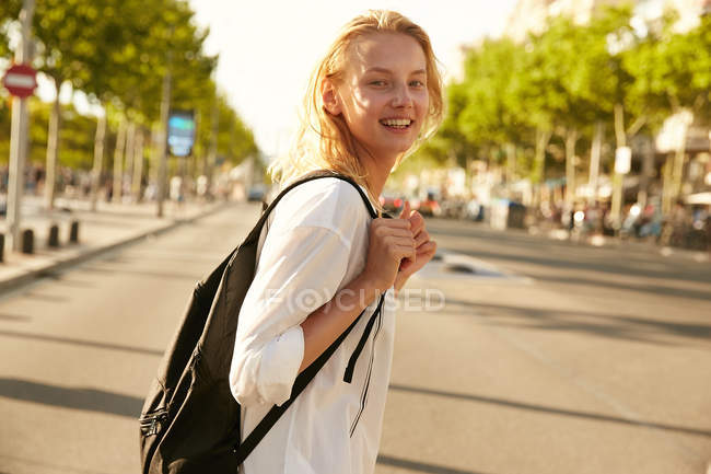 Young smiling woman walking with bag on street and looking at camera in barcelona — Stock Photo