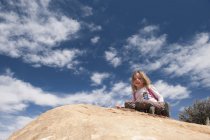 Little girl sitting on top of rock, portrait — Stock Photo