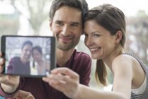 Pareja usando tableta digital para tomar una selfie - foto de stock
