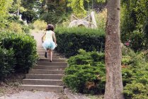 Девушка в пачке бежит вверх по лестнице в парке, вид сзади — стоковое фото