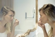 Donna che applica cosmetici nello specchio — Foto stock