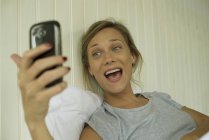 Souriant femme prendre selfie dans le lit — Photo de stock