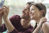 Paar posiert mit Smartphone für ein Selfie — Stockfoto