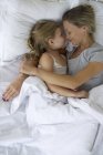 Mother and daughter in bed embracing — Stock Photo