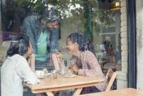 Camarero hablando con los clientes en la cafetería - foto de stock