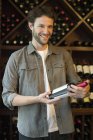 Smiling Shopper selecting bottle of wine — Stock Photo