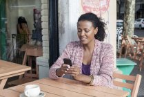 Woman using cell phone at sidewalk cafe — Stock Photo