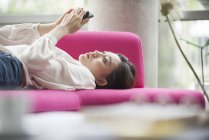 Жінка розслабляється вдома за допомогою смартфона — стокове фото