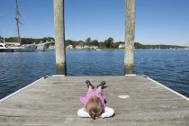 Bambina sdraiata sul molo con le mani dietro la testa — Foto stock