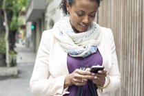 Афроамериканська жінка використовує мобільний телефон на відкритому повітрі — стокове фото