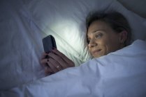 Femme au lit avec smartphone — Photo de stock
