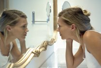Жінка дивиться на себе у дзеркало у ванній — стокове фото