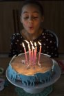 Chica soplando velas en pastel de cumpleaños - foto de stock
