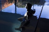 Africano americano hombre relajante en piscina cubierta - foto de stock