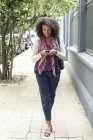 Mujer mensaje de texto mientras camina en la acera - foto de stock