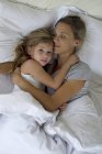 Мать и дочь в постели обнимаются — стоковое фото