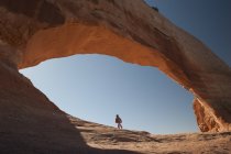 Child walking under natural arch in Utah, USA — Stock Photo