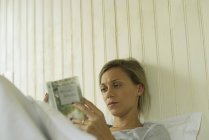 Giovane donna che legge a letto — Foto stock