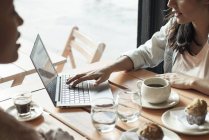 Las mujeres que utilizan ordenador portátil en la cafetería - foto de stock