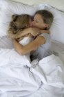 Mère et fille au lit embrassant — Photo de stock