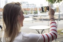 Молодая женщина позирует для селфи в кафе на открытом воздухе — стоковое фото