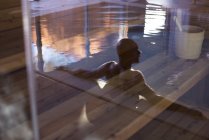 Homem relaxante na piscina, refletido na porta de vidro — Fotografia de Stock