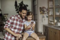 Vater und Tochter schauen gemeinsam aufs Smartphone — Stockfoto