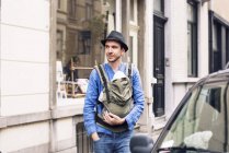Man with baby in carrier on the move in the city — Stock Photo