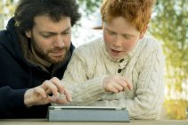 Père et fils regardant ensemble tablette numérique — Photo de stock