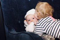 Toddler embracing infant sibling — Stock Photo