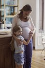 Schwangere Frau mit kleiner Tochter umarmt in der Küche — Stockfoto