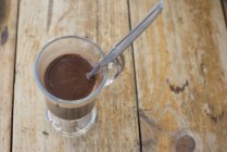 Крупный план горячего шоколада в стакане с ложкой — стоковое фото