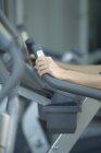 Imagen recortada de la mujer utilizando la máquina de ejercicio en el gimnasio - foto de stock