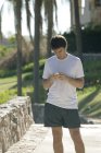 Joggerin checkt Smartphone im Park — Stockfoto
