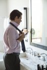 Мужчина одевается, настраивает галстук в зеркало — стоковое фото