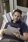 Mann mit digitalem Tablet auf dem Bett liegend — Stockfoto